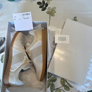 Maison Margiela inside out  - Allt original ingår. Köpts från highsnobetiy. Endast används i tre dagar men passar tyvärr inte mig i storleken. Snygga vita sneakers från Maison Margiela med beige detaljer och gummisula. Skorna har en klassisk design med snörning och rund tå. Perfekta för en stilren look.