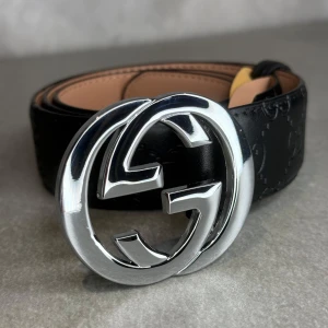 Svart GG bälte - Svart skärp från GG, Bältet har ett diskret mönster med märkets logga präglad längs hela remmen. Perfekt för att sätta en lyxig touch till din outfit. Storlek 110cm.                                                    Helt ny, kommer med GG-lådan.                                                   För mer information kontakta oss gärna privat. Priset kan 100% diskuteras!!!