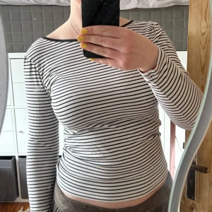 Randig långärmad topp från Lindex - Säljer en till stilren randig topp från Lindex i svart och vit. Även denna med jättefin öppen rygg!🩷