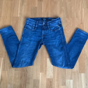 Blå jeans från Replay - Snygga blå jeans från Replay i modellen Anbass. De har en klassisk femficksdesign och en bekväm passform. Perfekta för en stilren look. Den har en liten fläck på baksidan som knappt är synlig. Det är bara att skriva om du har några frågor!👍🏼