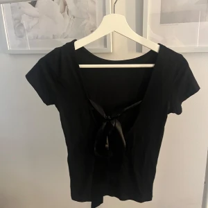 Svart topp med knytning i ryggen - Snygg svart topp med knytning i ryggen 🤩 endast provad. Modell: MARTA BOW TOPP. 95% viskos. Skriv meddelande vid frågor/fler bilder 🩷