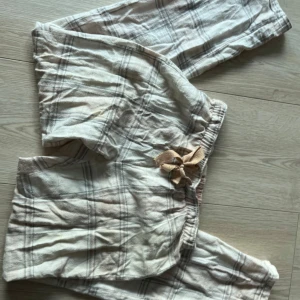 Rutig byxa med rosett från Lindex - Säljer en mysig rutig byxa från Lindex i ljusa färger. Byxan har en söt rosett framtill och elastisk midja för extra komfort. Perfekt för en avslappnad stil.🩷🩷