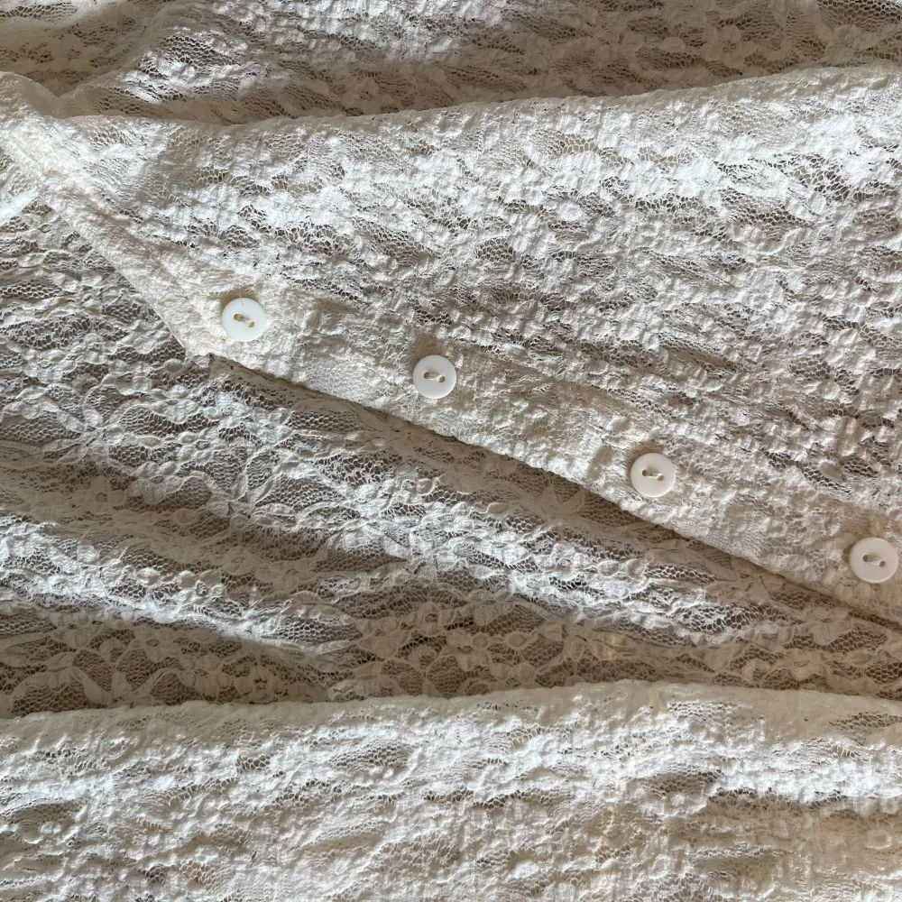 Säljer en elegant vit spetskofta från Stradivarius. Koftan har långa ärmar och knappar framtill. Perfekt för en stilren look med vackra spetsdetaljer. Passar utmärkt för speciella tillfällen.. Mekot.