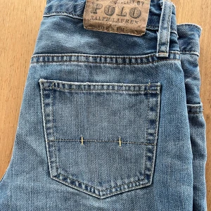 Blå jeans från Polo Ralph Lauren - Säljer ett par klassiska blå jeans från Polo Ralph Lauren i bra skick. De har en straight passform och är tillverkade i 100% bomull. Perfekta för vardagsbruk och kan enkelt matchas med olika outfits. Passar både till höst och vår.