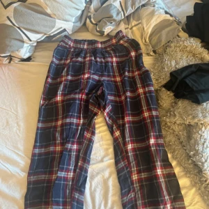 Rutig pyjamasbyxa Nightwear S - Mysiga rutig pyjamasbyxor från Nightwear i storlek S. Byxorna har elastisk midja och är i mjuk bomull med mörkblå, röda och vita rutor. Perfekta för chill hemma eller när du vill vara extra bekväm. Klassisk loose fit och skön känsla mot huden.