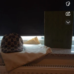 Gucci keps  - Snygg keps från Gucci med klassiskt GG-mönster i beige och brunt. Kepsen har justerbar rem bak i skinn och är tillverkad i ett strukturerat syntetmaterial. Perfekt för dig som vill ha en lyxig och trendig accessoar med tydlig designerstil.