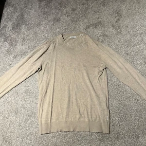 Beige stickad tröja Jack & Jones - Säljer en stilren beige stickad tröja från Jack & Jones i storlek S. Tröjan har rund hals, långa ärmar och ribbade muddar vid ärmslut och nederkant. Perfekt för dig som gillar enkel och clean look. Nypris 499