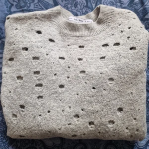 Grå stickad tröja från & Other Stories  - Grå stickad tröja med unikt hålmönster över tröjan som ger en trendig vibe. 