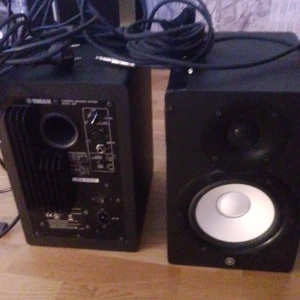 Yamaha Hs7 - Bilderna visar ett par Yamaha HS7 aktiva studiomonitorer, perfekta för dig som vill ta din musikproduktion till nästa nivå. Med kraftfullt ljud och tydlig diskant är de ett måste för hemmastudion eller gaminghörnan. Kablar ingår för enkel anslutning.