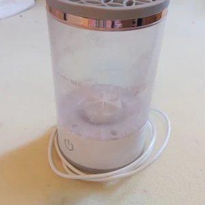 Sminkkylskåp med USB-sladd - Säljer ett sminkkylskåp i cylinderform med transparent plast och grått lock med dekorativt mönster. Har en snygg roséguldsdetalj upptill och USB-sladd för ström. Perfekt för att hålla dina hudvårdsprodukter och smink svalt och fräscht.