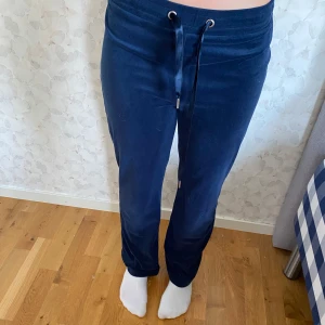 Marinblå mjukisbyxor från Gina Tricot - Snygga marinblå mjukisbyxor från Gina Tricot i storlek S. Byxorna har en loose passform, hög midja och snörning i midjan för extra komfort. Materialet är mjukt och skönt, perfekt för chill dagar. Enkla att matcha med en hoodie eller t-shirt.