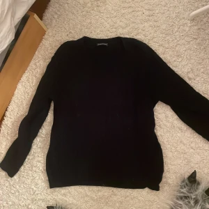 Mörkblå kabelstickad tröja - Mörkblå kabelstickad tröja med rund hals och lång ärm. Tröjan har ett klassiskt flätmönster som ger en snygg och tidlös look. Perfekt att matcha med jeans eller kjol för en chill stil. Materialet är mjukt och stickat, vilket gör den skön att bära under kyliga dagar.