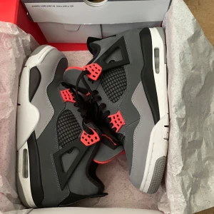 Jordan 4 Retro - Nike Air Jordan 4 Retro sneakers i mörkgrå och ljusgrå med svarta meshpaneler och detaljer i rött. Skorna har synlig Air-sula, snörning och Perfekt för dig som vill sticka ut.