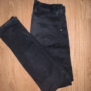 Replay Anbass Hyperflex  mörkgråa jeans - Mörkgråa replay Anbass Hyperflex jeans med slim passform och klassisk femficksdesign. Stretchigt material som ger grym komfort och rörelsefrihet. Snygga detaljer med Replay-logga på fickan och svart patch bak i midjan. Perfekta för dig som gillar stilrena och moderna jeans.