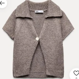 Beige stickad kofta från Zara - Säljer en mysig beige stickad kofta från Zara med korta ärmar och en stor krage. Koftan har en enkel knapp framtill och ribbade kanter. 