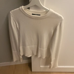 Vit stickad tröja från Bik Bok - Säljer en vit stickad tröja från Bik Bok i storlek S. Tröjan har rund hals, långa ärmar och breda ribbade muddar vid ärmslut och nederkant. Stilren och enkel design som är lätt att matcha med jeans eller kjol. Perfekt för dig som gillar en clean look.