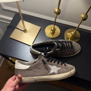 Golden Goose - Säljer ett par snygga Golden Goose sneakers i beige mocka med vit stjärndetalj på sidan och vit häl. Unika och snygga, dustbag medföljer. Möts på Östermalm eller fraktar. Väldigt bra skick.