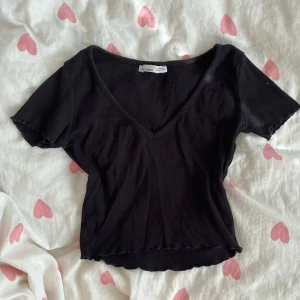 Svart ribbad croppad topp Pull & Bear - Svart ribbad croppad topp från Pull & Bear i strl S med v-ringad hals. Kortärmad och figurnära passform!💞