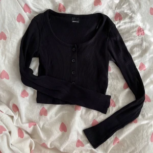 Svart ribbad croppad tröja / kofta - Svart croppad tröja / kofta från Gina Tricot i strl S med ribbad struktur och rundad hals. Lång ärmar med fem svarta knappar framtill (går att knäppa)!💞