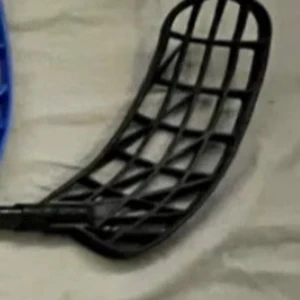 Innebandyblad - Ingen bok syns på bilden, endast en närbild av ett svart plastgaller som liknar bladet på en innebandyklubba. Ingen information om boktitel, författare eller innehåll kan utläsas.