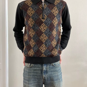 Mönstrad pikétröja från Fucking Awesome - Säljer en unik pikétröja från Fucking Awesome i storlek S. Tröjan har ett rutigt mönster i svart, brun, grå och gul med half zip framtill och krage. Materialet är 100% polyester och den har långa svarta ärmar samt ribbade muddar. 