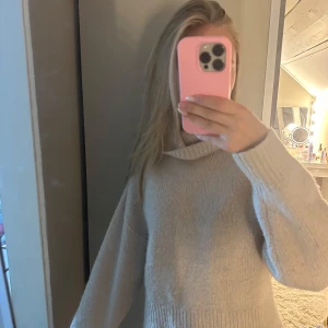 Beige stickad polotröja - Mysig beige stickad polotröja med bred krage och långa ärmar. Tröjan har en loose passform och ribbade muddar vid ärmslut och nederkant. 