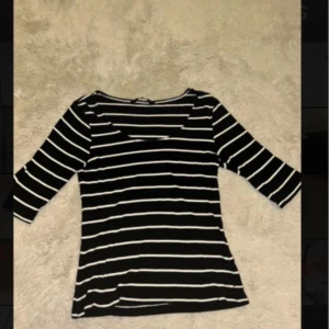 Svartvit randig topp från LCW Vision - Säljer en svart topp med vita horisontella ränder från LCW Vision. Modellen har rund hals och trekvartsärm, vilket ger en chill och stilren vibe. Materialet är mjukt och stretchigt, perfekt för dig som gillar bekväma och snygga plagg.