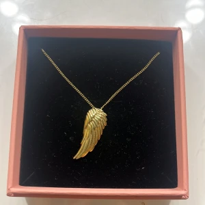 Guldigt halsband med vinge från Edblad - Snyggt halsband från Edblad med ett detaljerat hängsmycke i form av en guldig vinge. Kedjan är tunn och elegant, och vingen har en cool, skulpterad look som verkligen sticker ut. Perfekt för dig som gillar unika accessoarer med lite edge. Kedjan är ungefär 30 cm lång 💗, helt oanvänd 