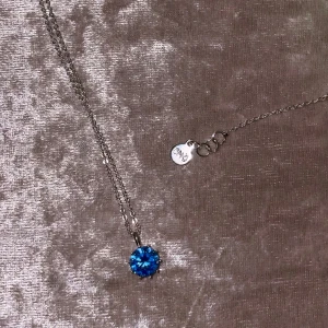 Halsband ”snö of sweden” - Säljer ett elegant halsband från SNÖ med en gnistrande blå rund sten i mitten. Kedjan är tunn och silverfärgad, perfekt för att ge en färgklick till din outfit. Äkta silver. Oanvänt.