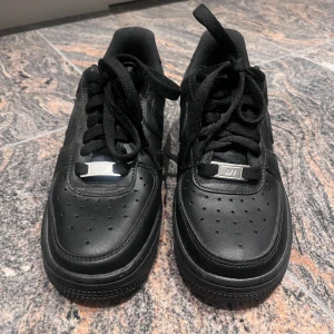 Svarta Nike Air Force 1 sneakers - Klassiska helsvarta Nike Air Force 1 sneakers med svart snörning och perforerad tå. Skorna har en låg siluett, rund tå och platt sula. Perfekta för dig som gillar en clean och tidlös look. Vi kan snacka mer om priset, så skriv privat!