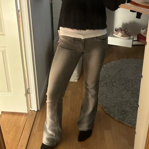 Grå Cheap Monday jeans - Snygga grå jeans med bootcut passform och låg midja. Storlek 30/32, Jag är 168cm. Passar mig som brukar ha S i vanliga fall. Midjemått rakt över: 38cm. Innerbenslängd: 80cm