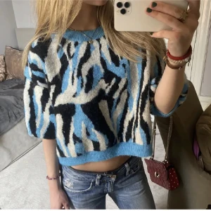 Blå och svart zebra stickad tröja - Säljer en croppad stickad tröja med blått, svart och vitt zebramönster. Tröjan har kortare ärmar och en lös passform. Som ny🦓💙🤍🖤öppen för prisförslag