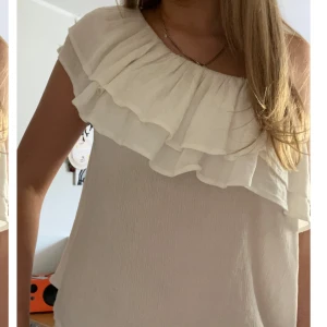 Volang topp  - Vit volang blus, som är off shoulder på ena armen. Använd men utan defekter, tunt material 