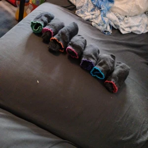 Svarta strumpor med färgglada kanter - Säljer flera par svarta strumpor med olika färgade kanter i grönt, rött, blått, lila, orange och rosa. Perfekta för dig som vill ha lite färg men ändå hålla det stilrent. Strumporna är i klassisk modell och passar till det mesta. St 36-38