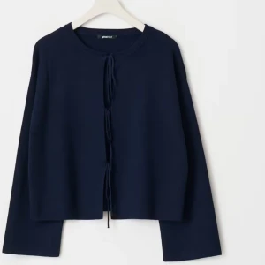 Mörkblå stickad tröja med knyt - Säljer en mörkblå stickad kofta från GinaTricot med knyt framtill. Koftan har lång ärm och en enkel, stilren design som passar perfekt till många outfits.