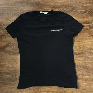 Svart t-shirt från Calvin Klein Jeans - Säljer en svart t-shirt från Calvin Klein Jeans med vit logotyp på bröstet. Klassisk passform och rund halsringning. Perfekt basplagg för garderoben.