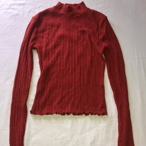 Röd ribbad topp  - Säljer en röd ribbad topp från Forever 21. Tröjan har lång ärm och tight passform. Materialet är stretchigt och mjukt.