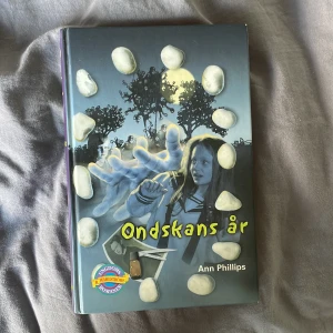 Ondskans år - Spännande ungdomsbok av Ann Phillips med ett mystiskt omslag där en flicka står i en cirkel av vita stenar. Boken ingår i B. Wahlströms ungdomsromaner och handlar om magi, vänskap och ondska.