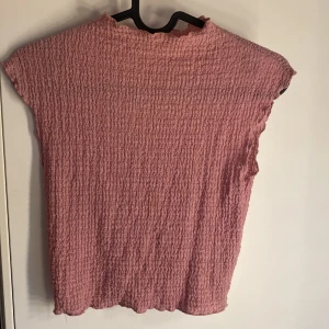 Rosa ribbad topp från Bershka - Säljer en rosa topp från Bershka med ribbad struktur. Toppen har korta ärmar och är tillverkad i ett mjukt, stretchigt material. Perfekt för vår och sommar! 💗Använd en gång!