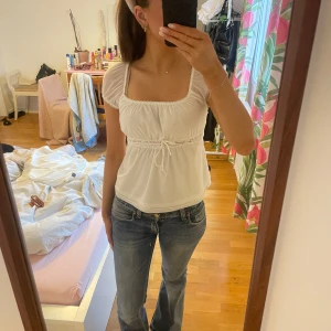 Vit blus med spetsdetaljer och puffärmar - Söt vit blus med puffärmar och spetsdetaljer under bysten. Blusen har knytband i midjan. Har tyvärr aldrig kommit till användning 