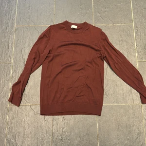Vinröd tröja från H&M - Säljer en vinröd långärmad tröja från H&M i slim fit-modell. Tröjan har rund halsringning och är tillverkad i ett mjukt material som passar perfekt för lager-på-lager. Enkel och stilren design.