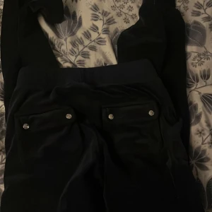 Mörk blåa byxor från Juicy Couture - Snygga svarta byxor från Juicy Couture med glittriga knappar på bakfickorna och snörning i midjan. Perfekt skick. Inga tecken på användning. Priset kan diskuteras