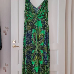 Långklänning från Indiska strl L - Säljer en långklänning från Indiska med v-ringning och vackert paisleymönster i grönt och blått. Klänningen har ärmlös design och mjukt, lätt material som passar perfekt för varma dagar. 100% bomull. Storlek L. Kan hämtas i Vallentuna.