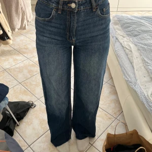 Blå raka jeans med medel\hög midja - Säljer ett par klassiska blå jeans med hög midja och raka ben. Jeansen har fem fickor, knapp och dragkedja framtill samt snygg tvättad look. Perfekta till vardags och lätta att styla med olika toppar. Pris går att diskutera.