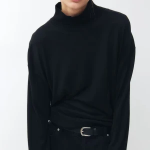 Svart polotröja i stickat material - En klassisk svart polotröja i mjukt stickat material. Tröjan har lång ärm och ribbade muddar vid hals, ärmslut och nederkant. Perfekt att styla till jeans eller kjol för en enkel och stilren look.