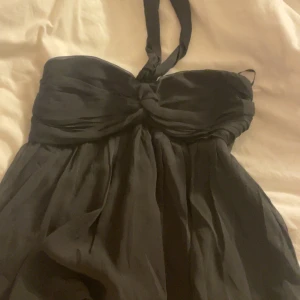 Svart halternecktopp från Nelly - Supersnygg svart topp från Nelly med halterneck och knutdetalj framtill. Man kan bära den på olika sätt, som man ser på bilderna. Säljer då jag inte tycker att den passade mig! Bra skick, använd köp nu🩷