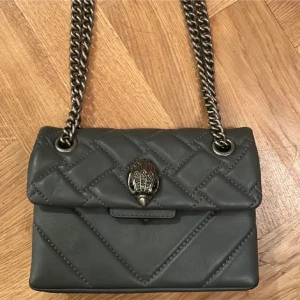 Grå Kurt geiger - En grå unik Kurt Geiger väska i den lilla storleken, väl använd men samtidigt sparsamt använd. Defekterna är inget som syns när väskan är på, bara underifrån! Därav priset! Pris kan diskuteras!