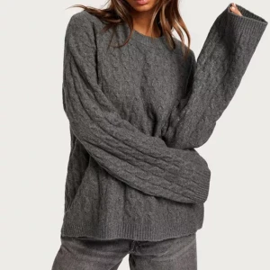 STICKAD - Fin oversized kabelstickad tröja från Nelly köpt för 399 kr, använd endast ett fåtal gånger och i fint skick! Säljer då jag har flera liknande tröjor och inte har plats 🩶