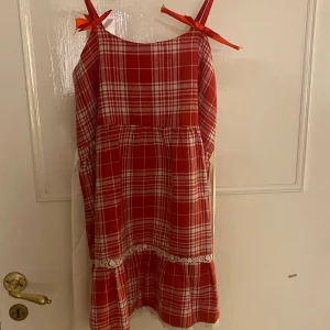 Röd klänning med detaljer  - Använd 1 gång. Gullig röd klänning med rosetter. Köparen står för frakten💕