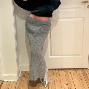 Stickad grå lång kjol  - Stickad grå kjol med slits. Passformen är tajt vid höfterna men utstickande ner till benen. Sitter super smickrande på kroppen. Väldigt bra kvalite på materialet. Super snygg till våren!  Storlek: S, men passar mig som har har storlek XS.